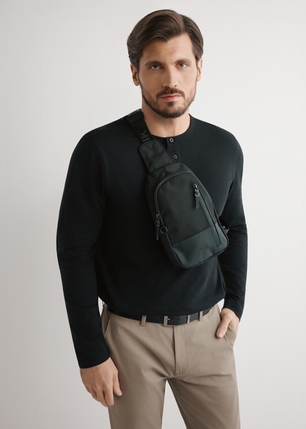 Czarna męska torba crossbody TORMN-0419-99(W26) - widok produktu na modelu, na jasnym tle. Widoczna sylwetka do kolan. 