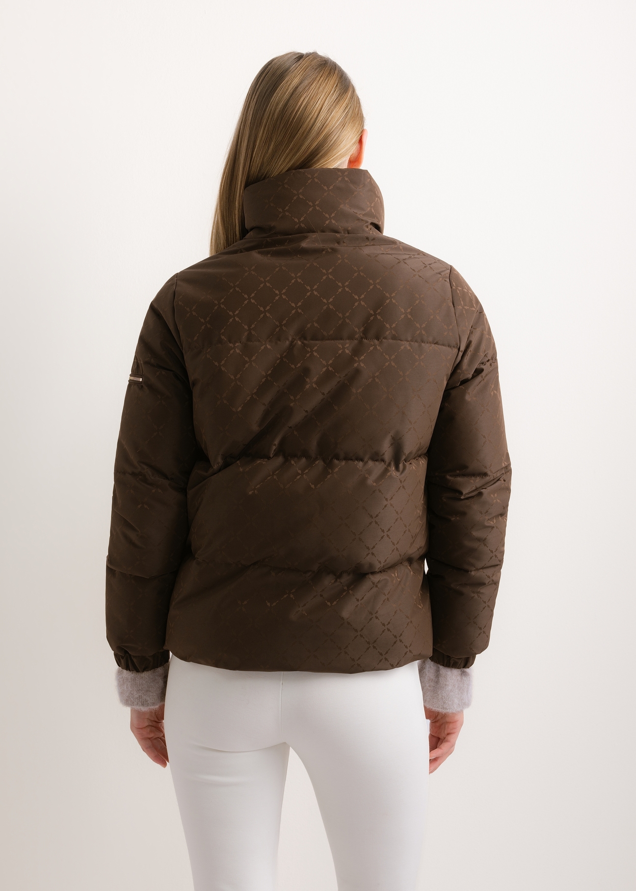 Ciemnobrązowa kurtka damska w monogram ze stójką KURDT-0694-1I(Z26), widok produktu od tyłu na modelce. Widoczna połowa sylwetki.