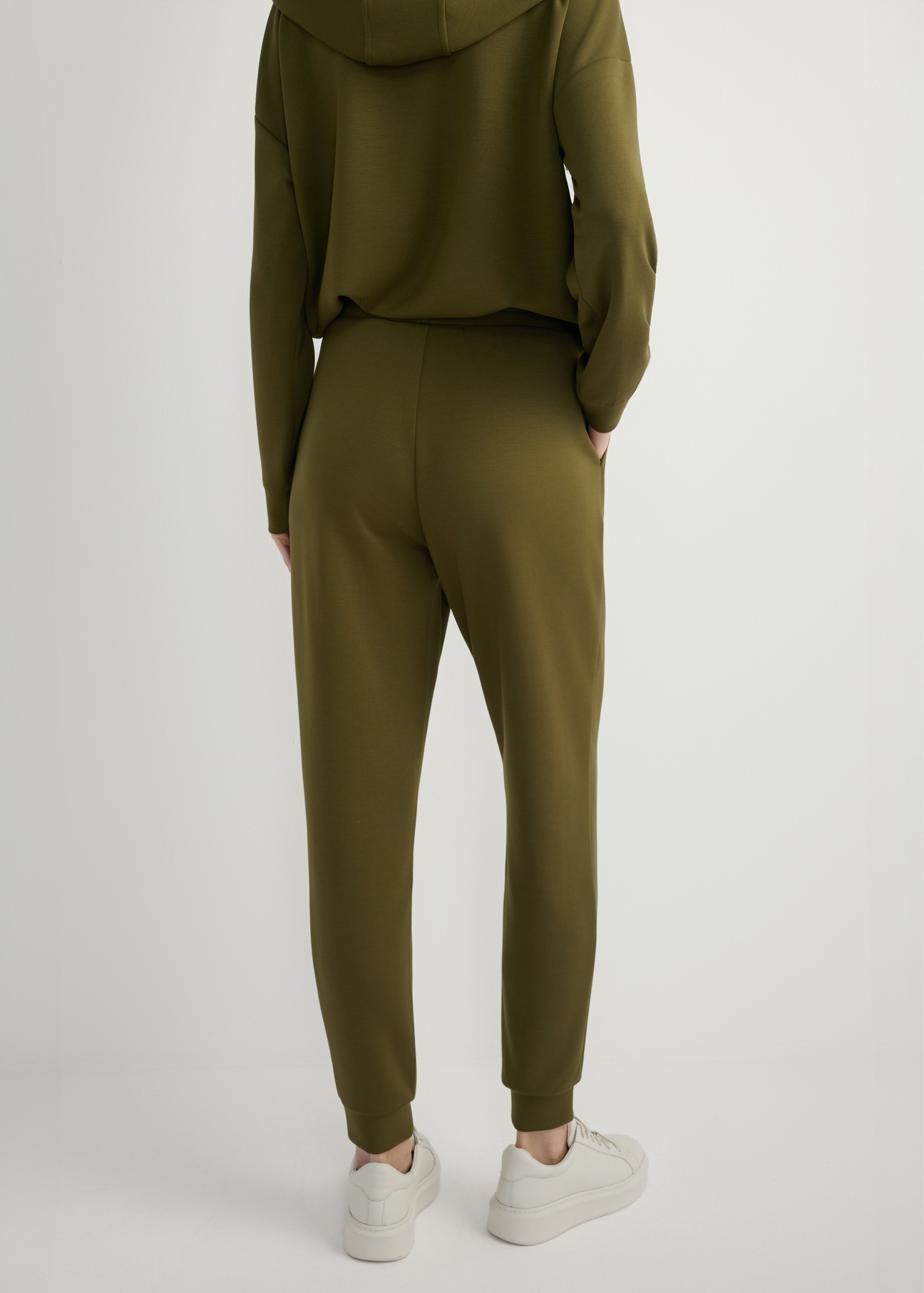 Spodnie damskie w kolorze khaki SPODT-0108-8D(W26), widok produktu z tyłu na modelce. Widoczna połowa sylwetki.