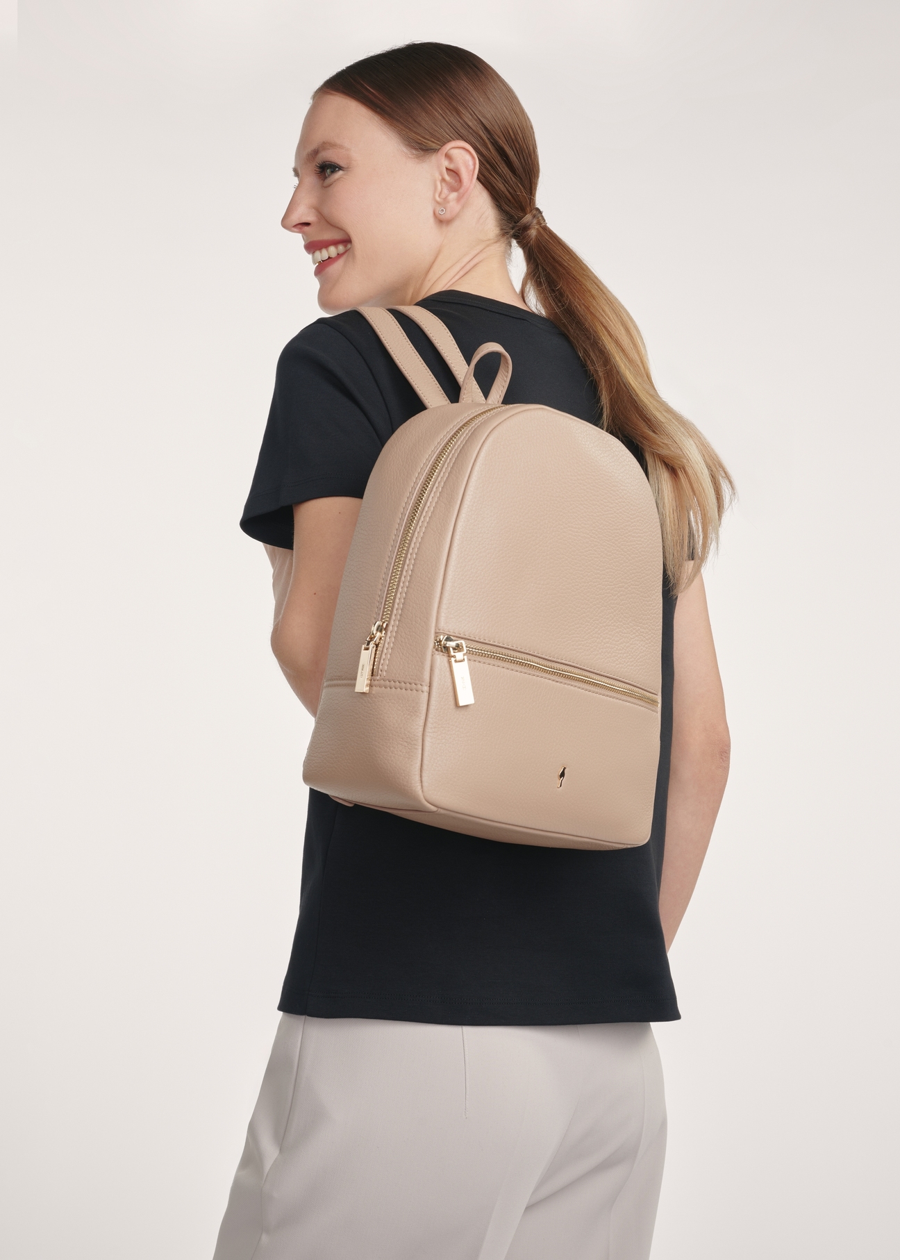 Beżowy skórzany plecak damski TORES-0898D-81(Z25), widok produktu przodem na modelce, widoczne pół sylwetki. 