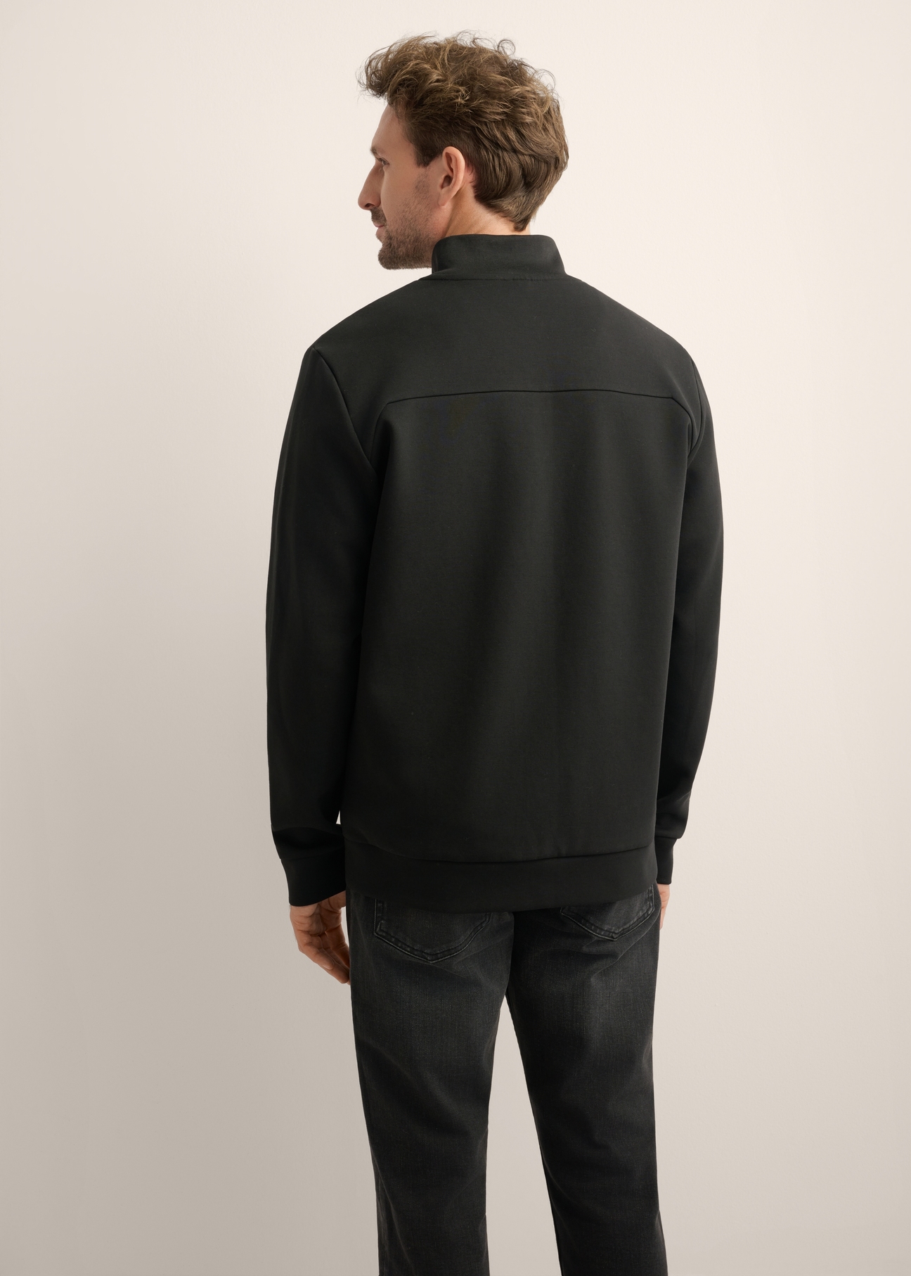 Rozpinana czarna bluza męska ze stójką BLZMT-0082-99(Z26), widok produktu z tyłu na modelu. Widoczna połowa sylwetki.