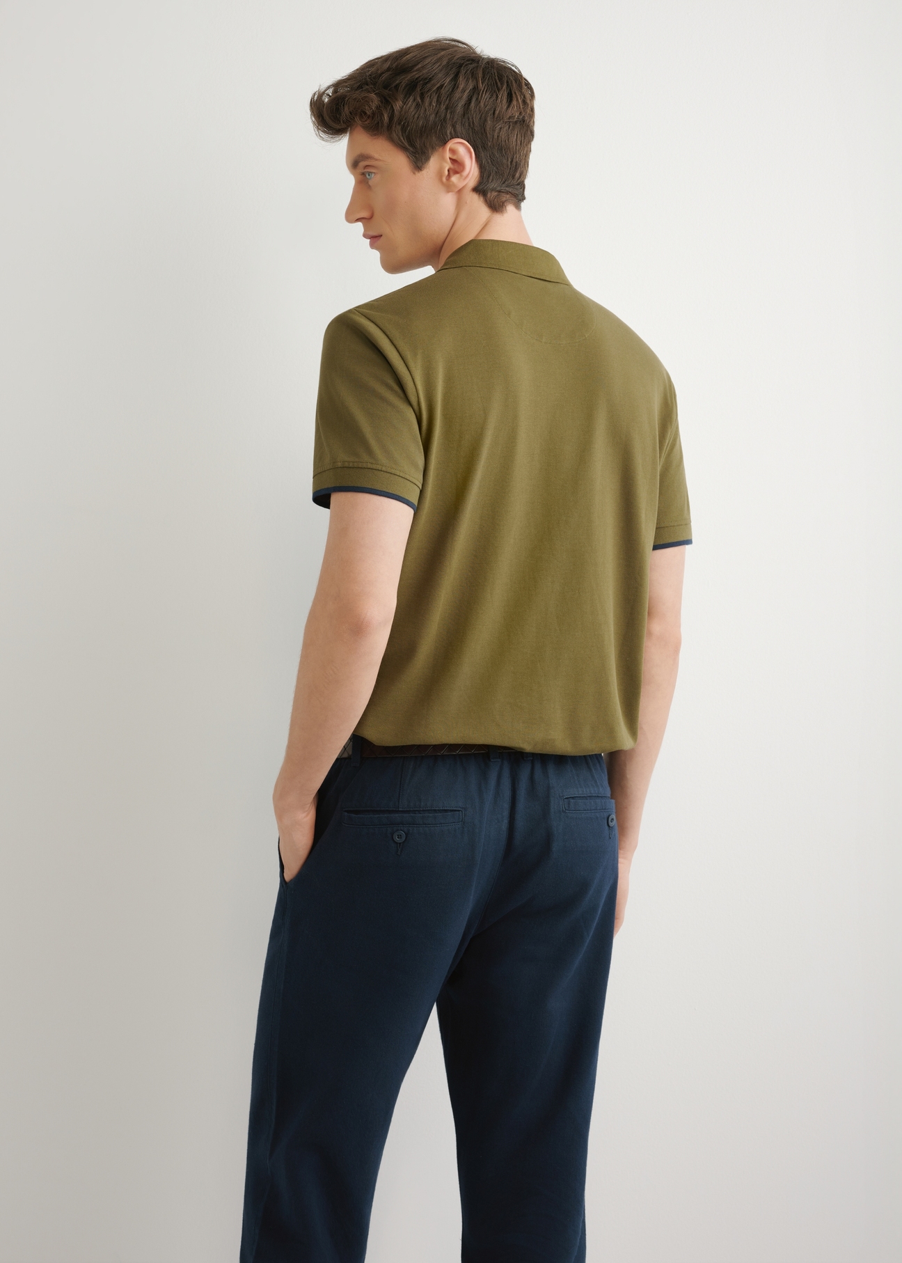 Bawełniana koszulka polo w kolorze khaki POLMT-0045B-8D(W26) - widok produktu z tyłu, na modelu na jasnym tle. Widoczna sylwetka do połowy.