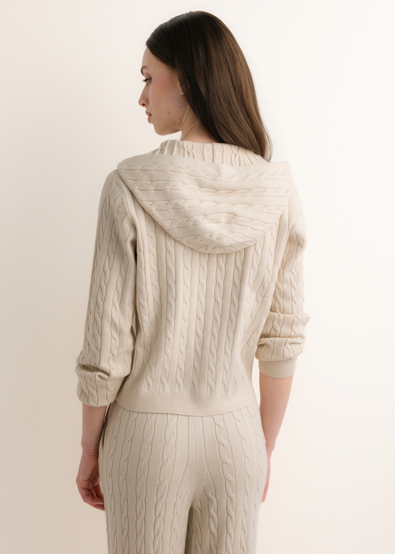 Beżowy sweter damski z kapturem BLZDT-0124-1A(Z26), widok produktu z tyłu na modelce. Widoczna połowa sylwetki.
