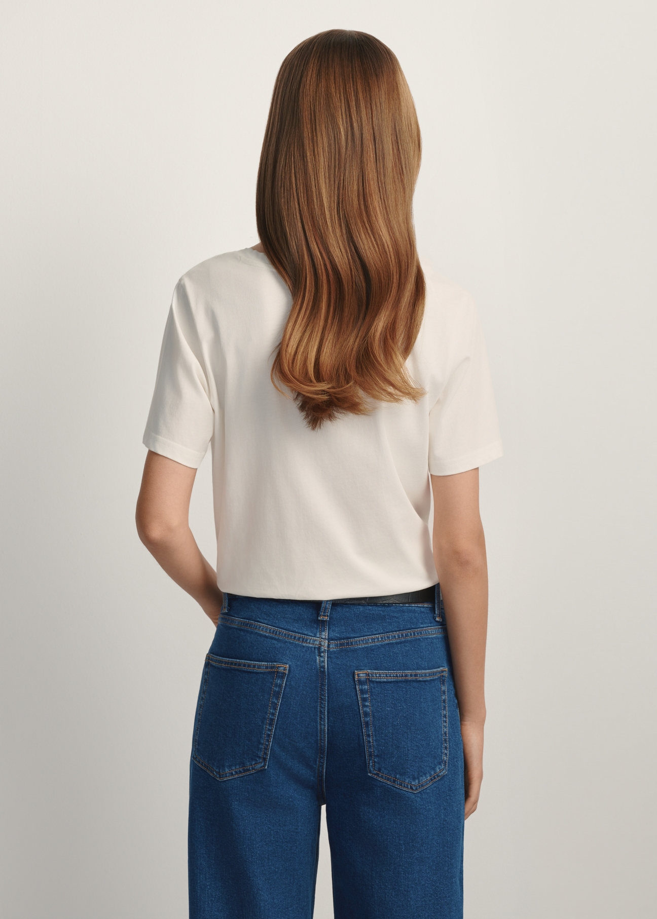 Kremowy T-shirt damski basic TSHDT-0120-0B(W26) - widok produktu z tyłu na modelce, na białym tle. Widoczna sylwetka do kolan. 