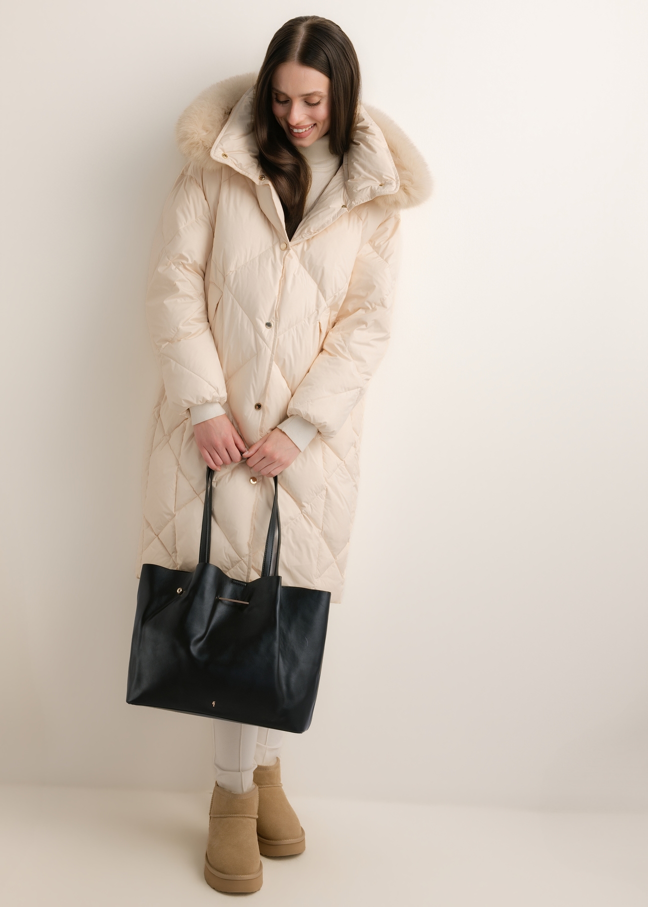 Czarna duża torebka shopper TOREC-1386-99(Z26), widok produktu z przodu w dłoniach modelki, na jasnym tle.
