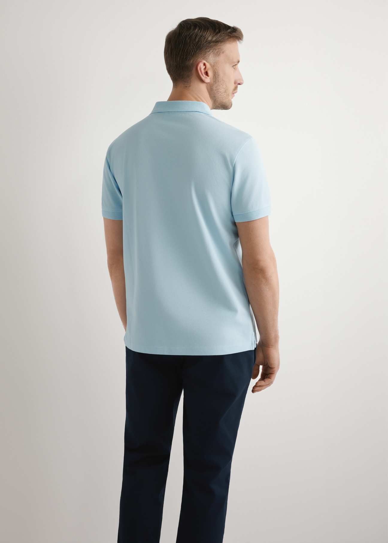 Błękitna koszulka polo męska POLMT-0089-7A(W26), widok produktu z tyłu na modelu. Widoczna połowa sylwetki.