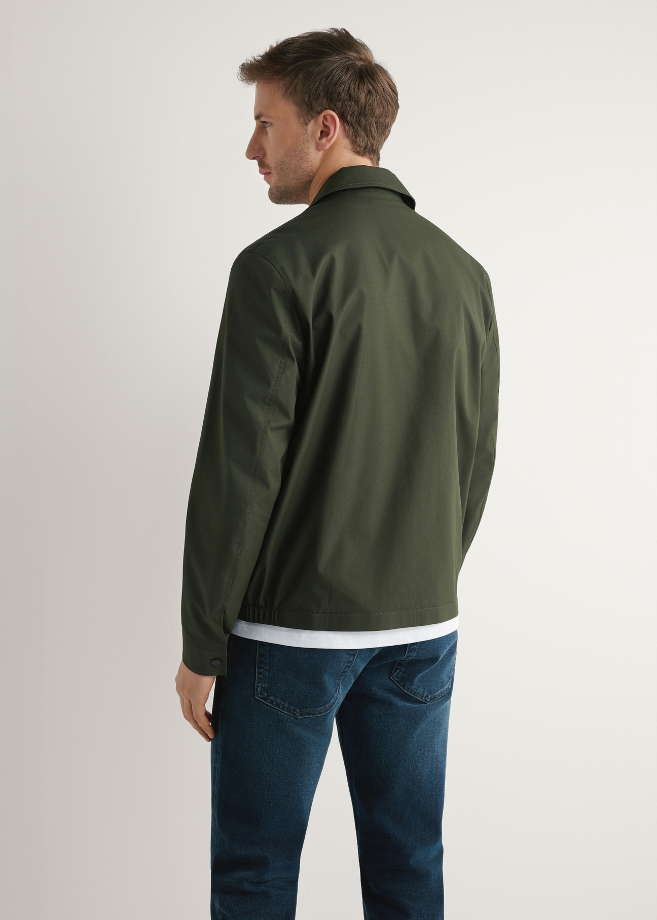 Przejściowa kurtka męska w kolorze khaki KURMT-0415-8D(W26), widok produktu z tyłu na modelu. Widoczna połowa sylwetki.