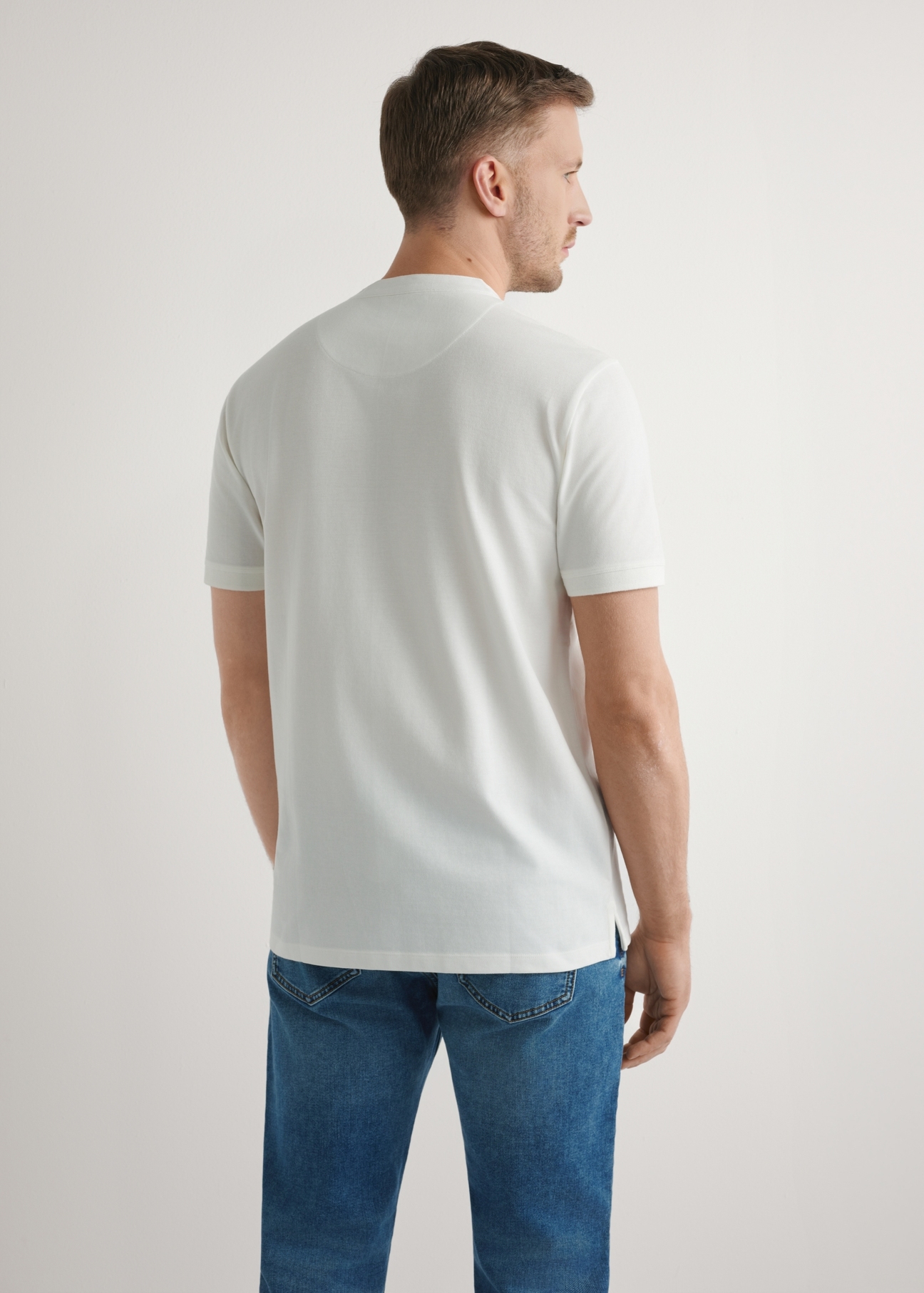 Kremowa koszulka polo męska POLMT-0061-0B(W26), widok produktu z tyłu na modelu. Widoczna połowa sylwetki.