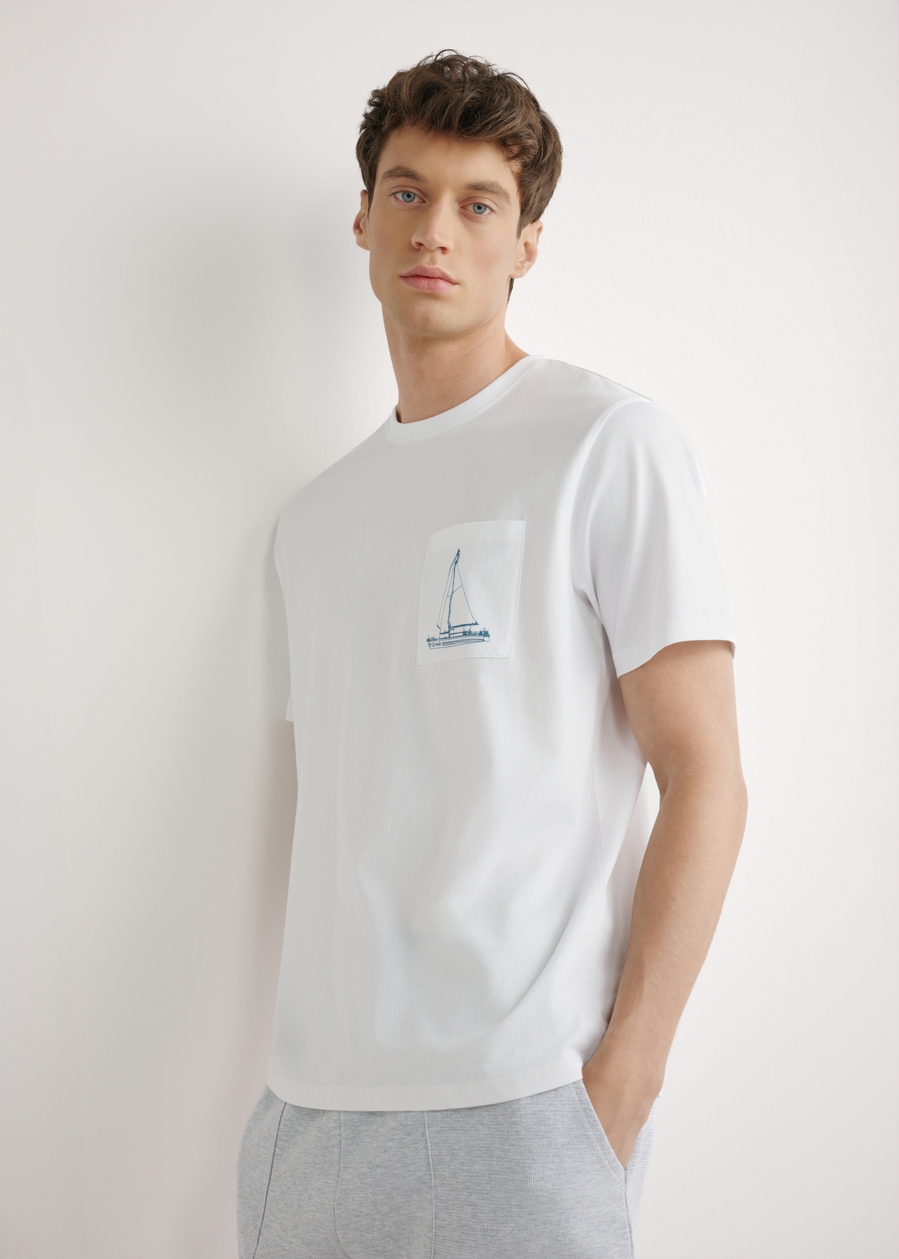 Biały T-shirt męski z nadrukiem TSHMT-0145-0A(W26), widok produktu z przodu na modelu. Widoczna połowa sylwetki.
