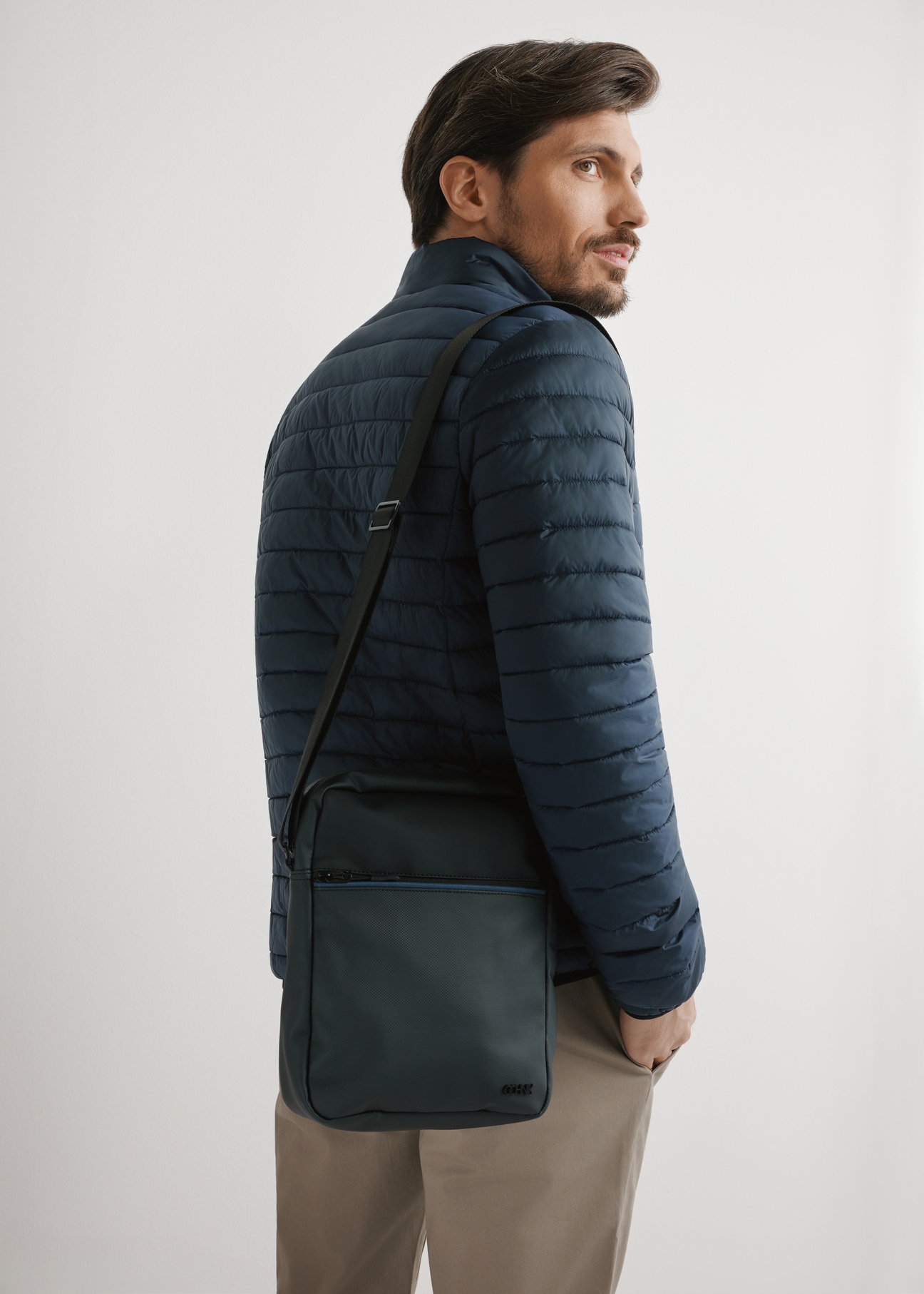 Czarna torba męska crossbody TORMN-0395-9J(W26) - widok produktu z przodu, na modelu, na jasnym tle. Widoczna sylwetka do połowy.