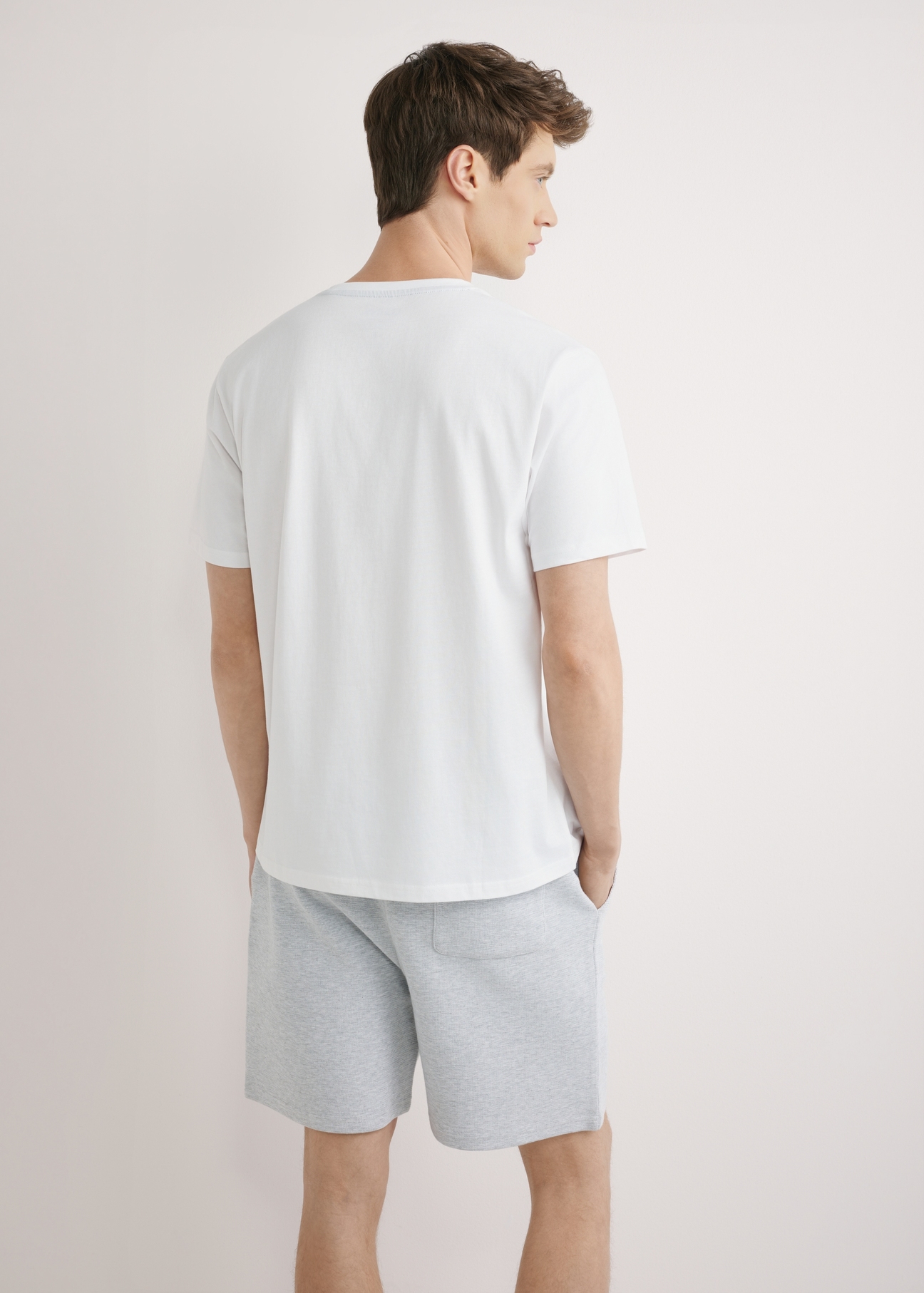 Biały T-shirt męski z nadrukiem TSHMT-0145-0A(W26), widok produktu z tyłu na modelu. Widoczna połowa sylwetki.