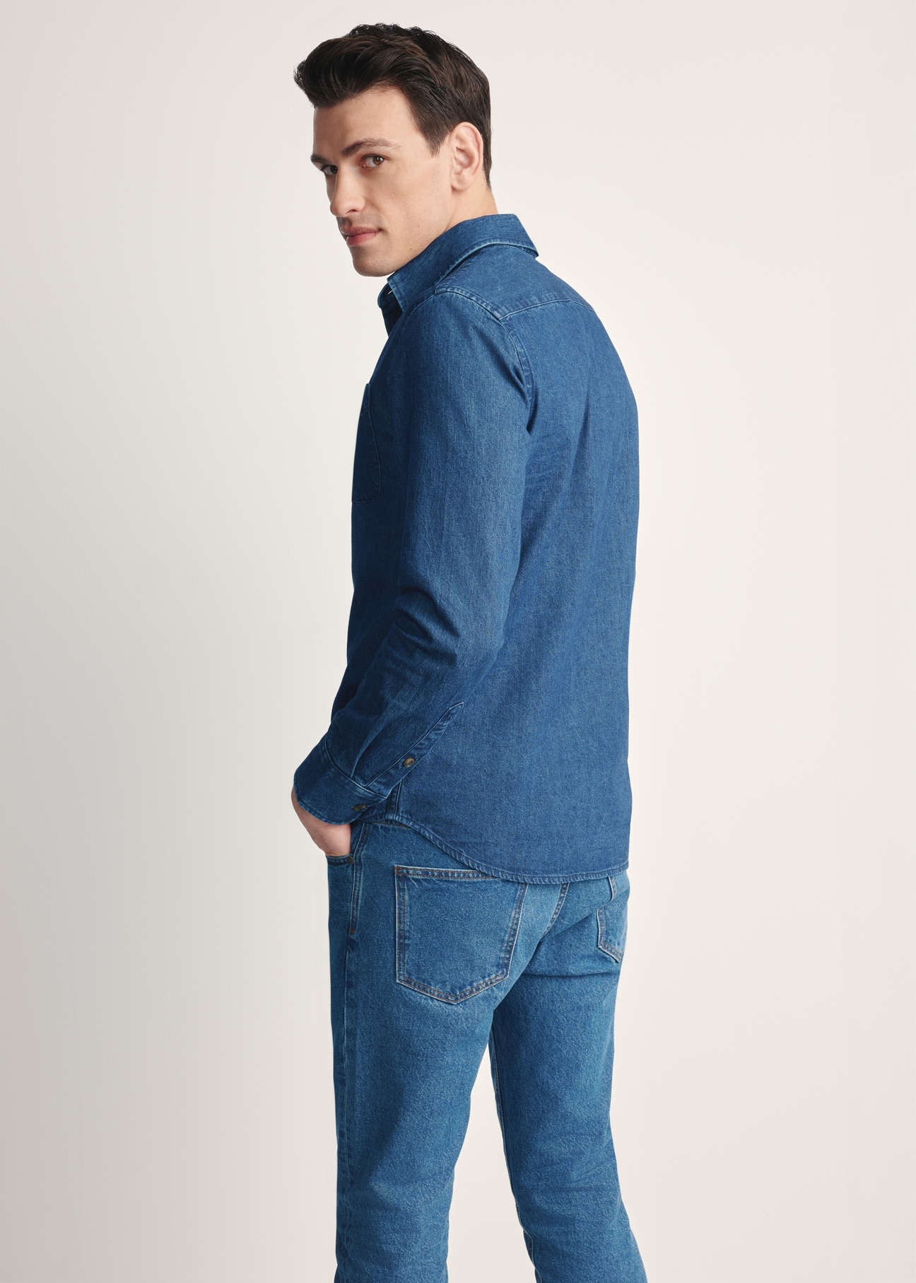 Niebieska jeansowa koszula męska KOSMT-0348-61(Z25), produkt widoczny od tyłu na modelu, widoczne pól sylwetki.