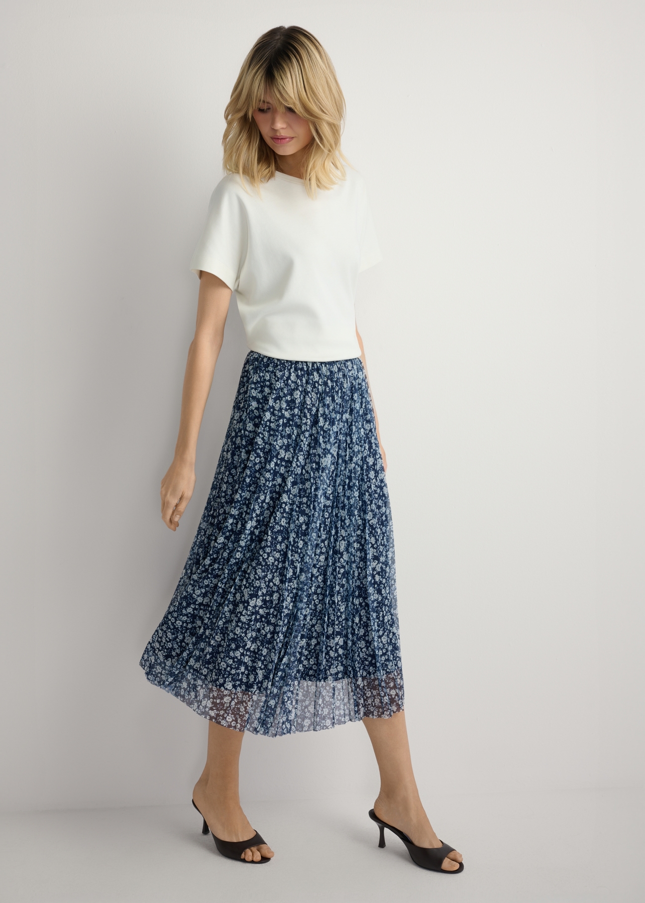 Spódnica plisowana midi w kwiaty SPCDT-0110-7P(W26), widok produktu z przodu na modelce. Widoczna cała sylwetka.