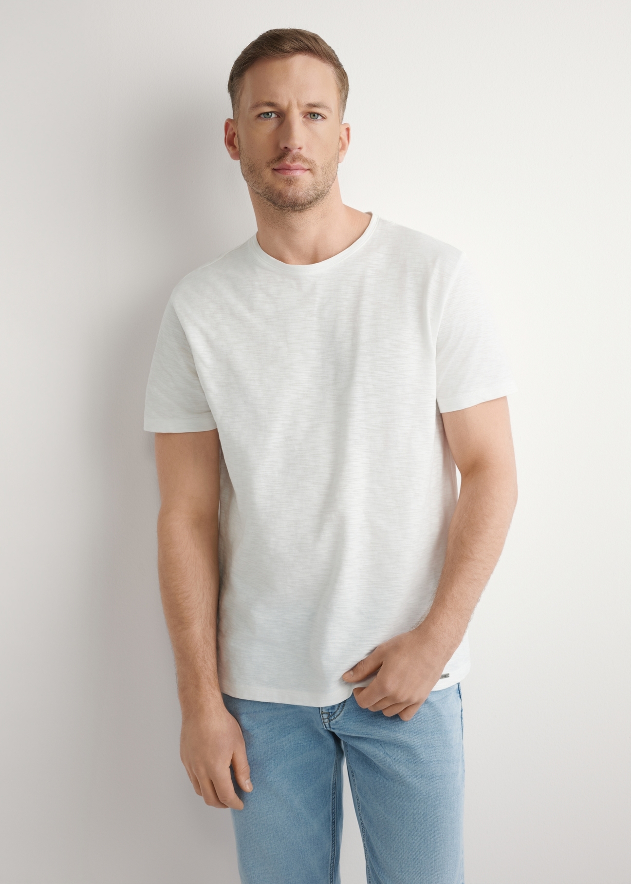 Bawełniany T-shirt męski w kolorze białym TSHMT-0149-0B(W26), widok produktu z przodu na modelu. Widoczna połowa sylwetki.