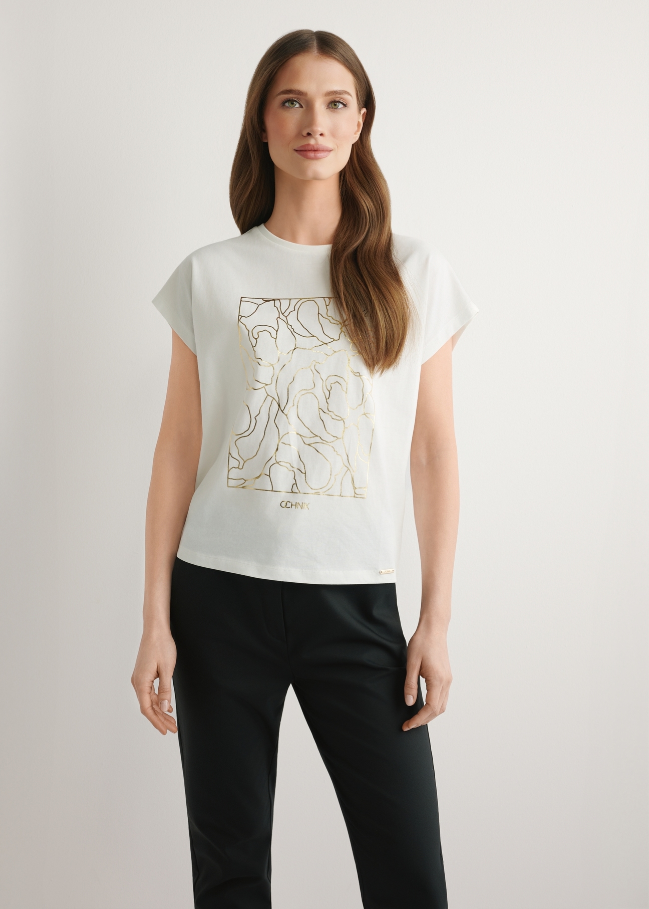 Kremowy T-shirt damski ze złotym nadrukiem TSHDT-0162-0B(W26), widok produktu z przodu na modelce. Widoczna połowa sylwetki.