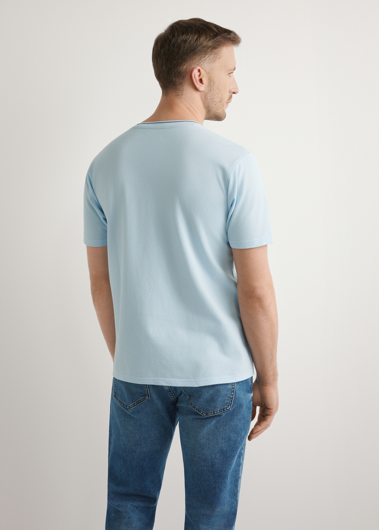 Jasnoniebieski T-shirt męski z bawełny TSHMT-0150-7A(W26), widok produktu z tyłu na modelu. Widoczna połowa sylwetki.