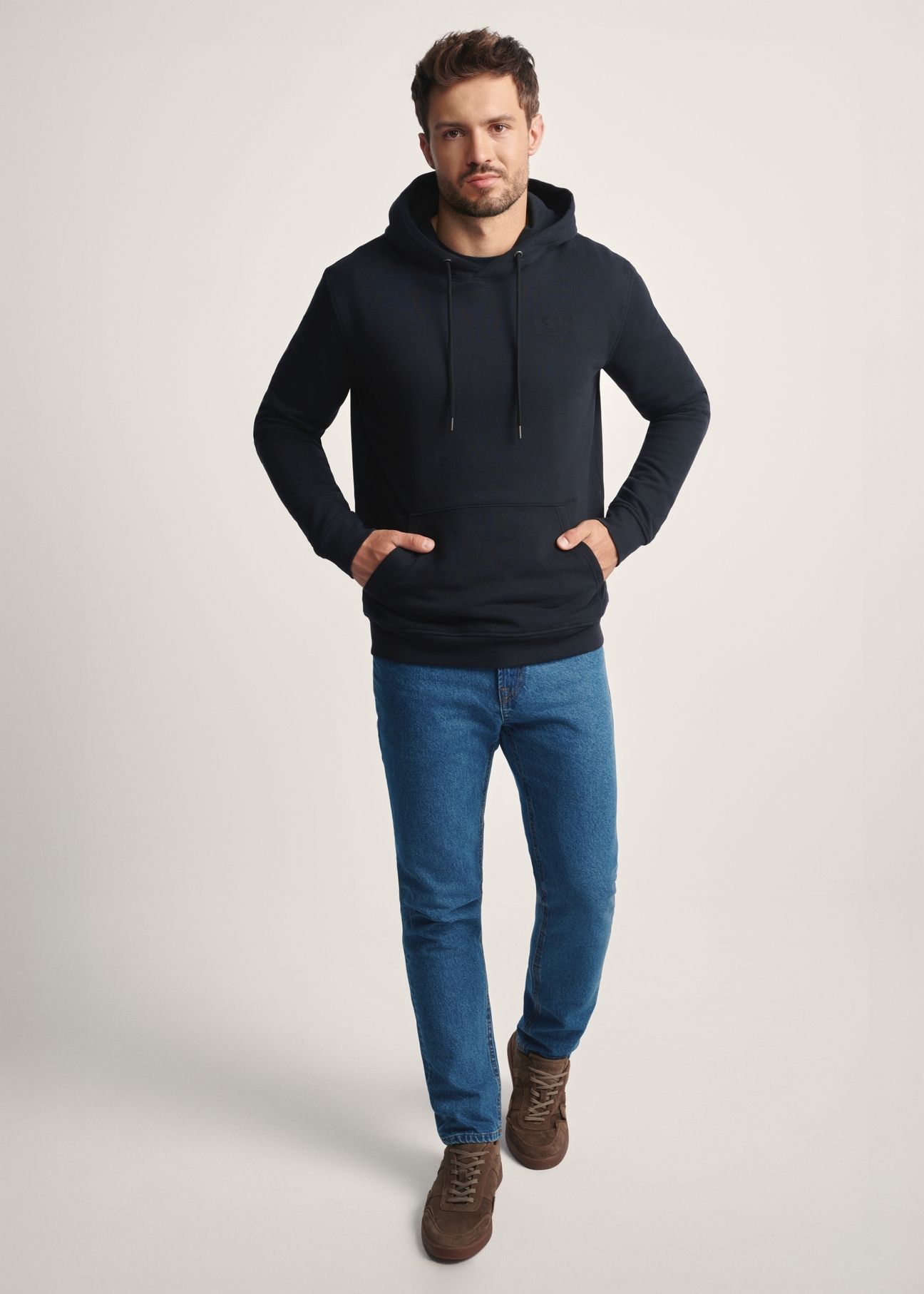 Czarna bluza męska z kapturem BLZMT-0073-99(Z25), widok produktu z przodu na modelu. Widoczna cała sylwetka.