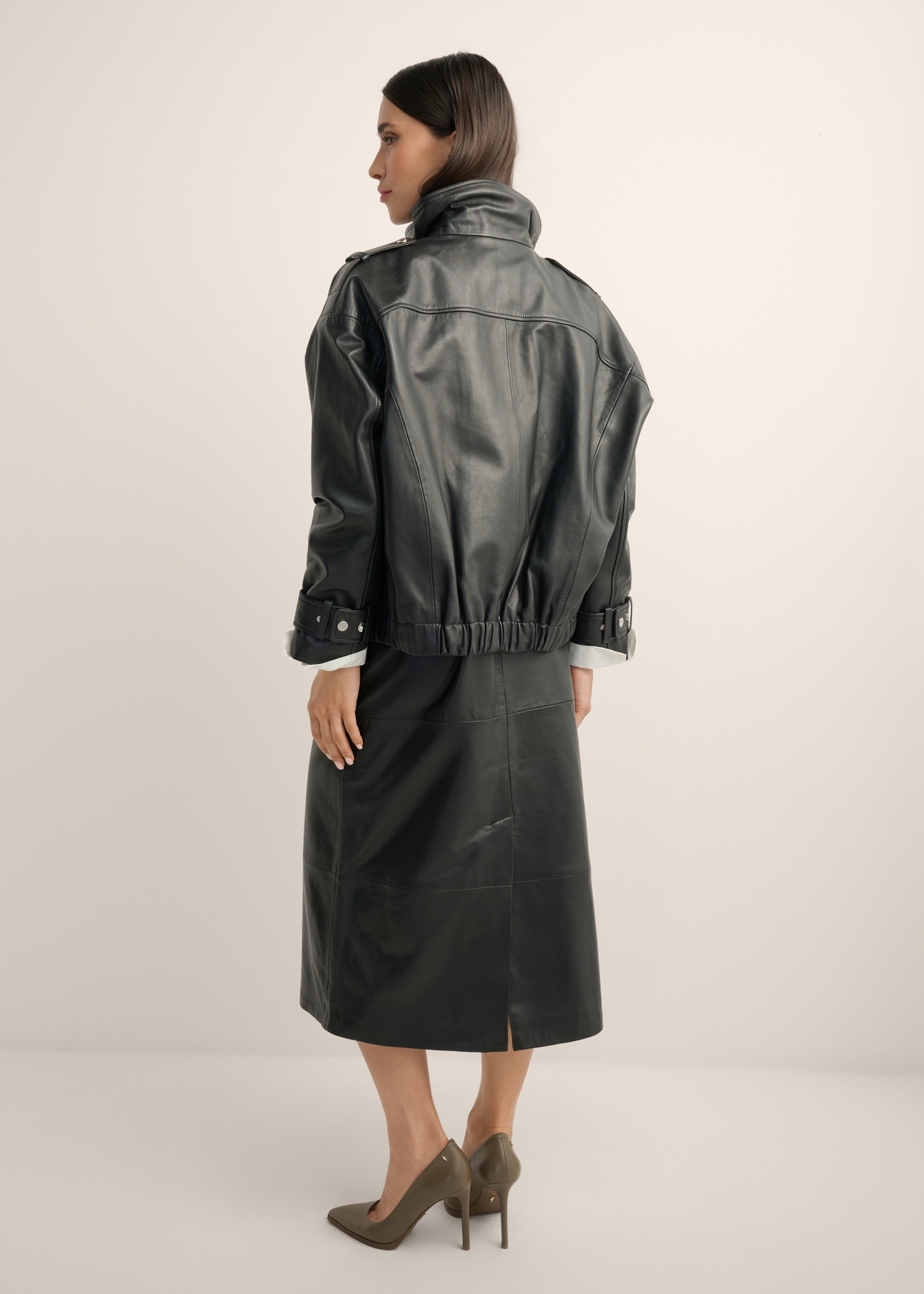 Czarna skórzana kurtka oversize KURDS-0623-99(Z26), widok produktu z tyłu na modelce. Widoczna cała sylwetka.