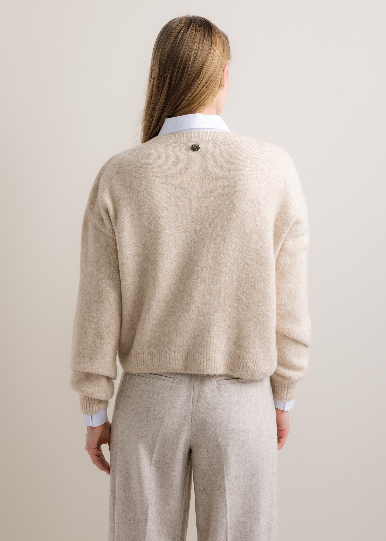 Jasnobeżowy sweter damski z domieszką wełny SWEDT-0271-1A(Z26), widok produktu z tyłu na modelce. Widoczna połowa sylwetki.
