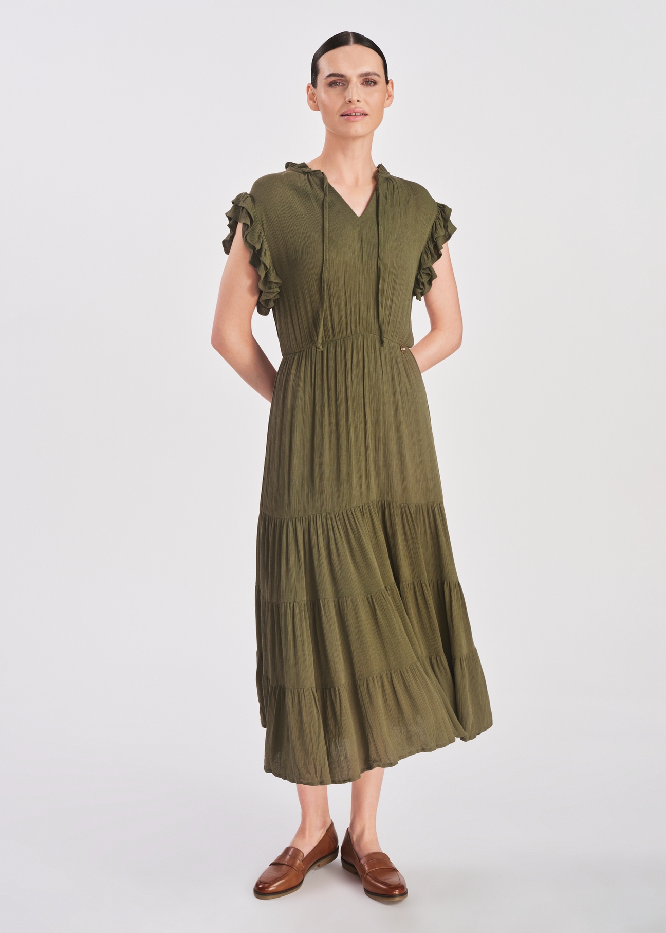 Długa sukienka w kolorze khaki SUKDT-0187-54(W25), widok produktu na modelce. Widoczna cała sylwetka.