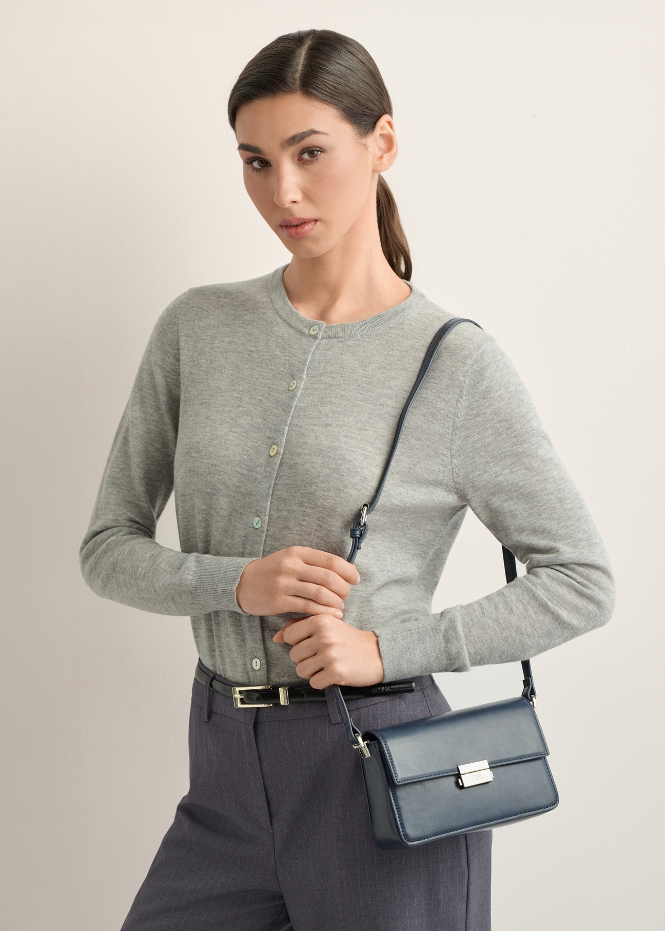 Elegancka granatowa torebka damska TOREC-1251-7E(Z26), widok skosu produktu na modelce. Widoczna połowa sylwetki. 
