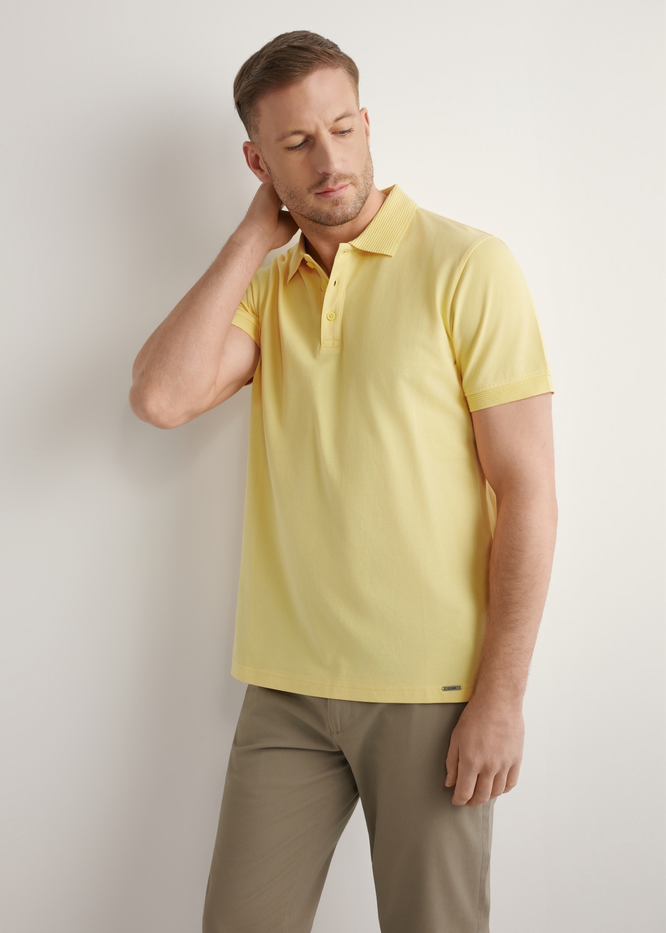 Żółta koszulka polo męska POLMT-0089-2B(W26), widok produktu z przodu na modelu. Widoczna połowa sylwetki.