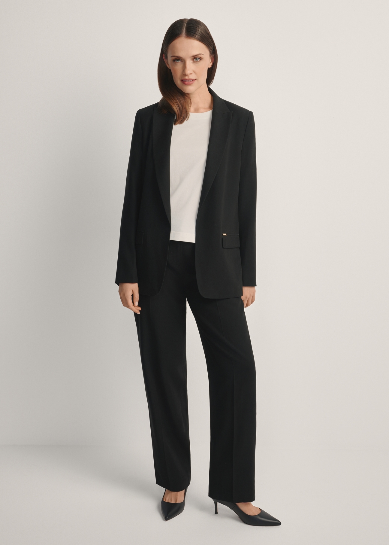 Czarne eleganckie spodnie damskie SPODT-0106A-99(W26), widok produktu od przodu na modelce, widoczna cała sylwetka.