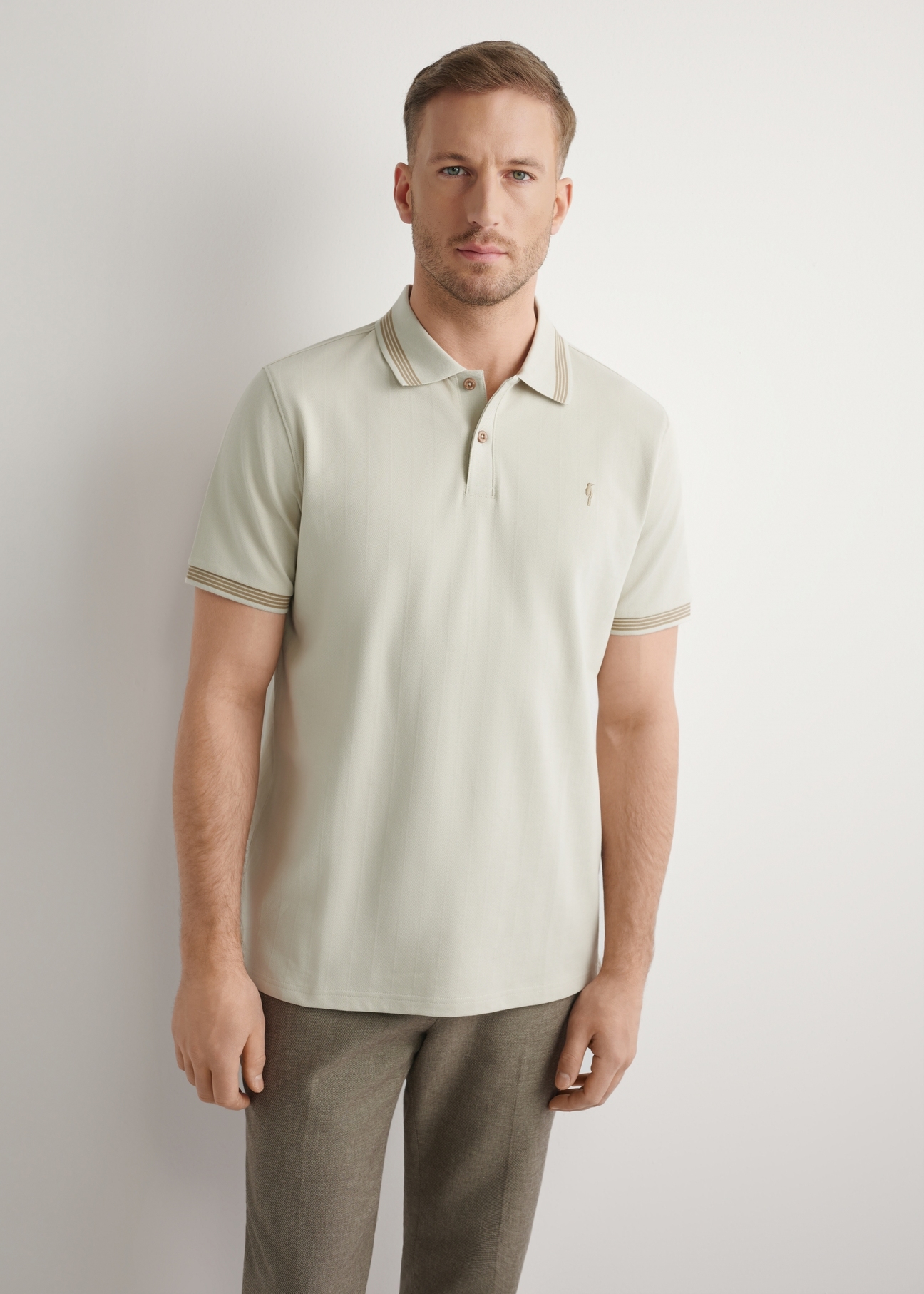 Koszulka polo w kolorze jasnego beżu POLMT-0090-1A(W26), widok produktu z przodu na modelu. Widoczna połowa sylwetki.