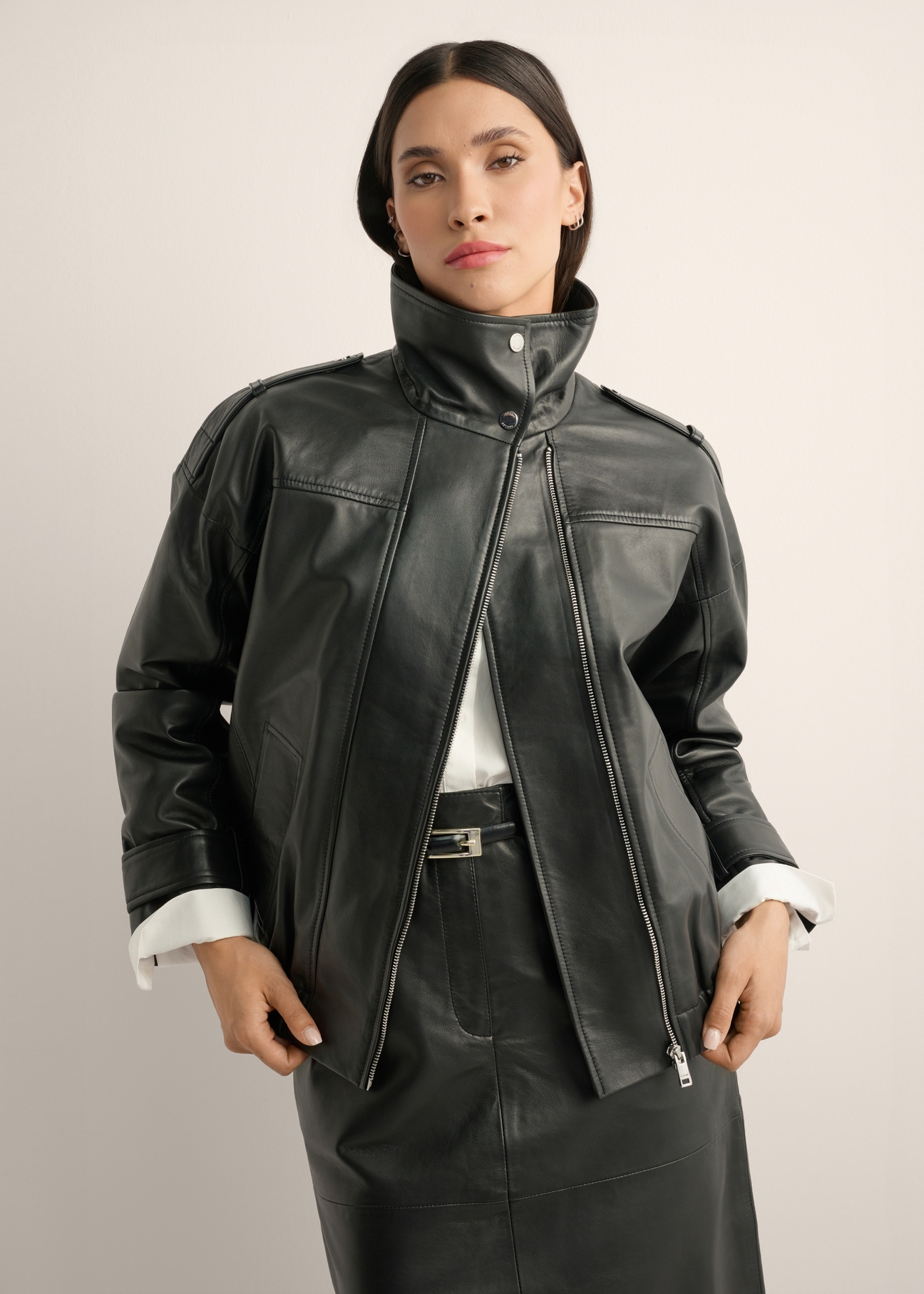 Czarna skórzana kurtka oversize KURDS-0623-99(Z26), widok produktu z przodu na modelce. Widoczna połowa sylwetki.