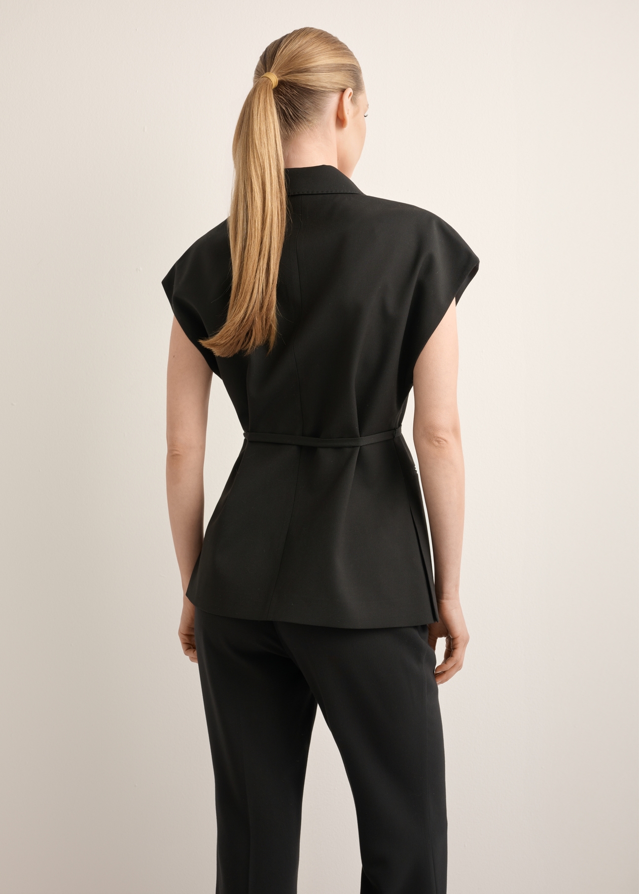 Czarna kamizelka garniturowa damska oversize KAMDT-0039-99(Z26), widok produktu z tyłu na modelce. Widoczna połowa sylwetki.