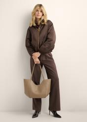 Beżowa torebka damska typu shopper TOREC-1296-1B (Z26), widok produktu w dłoni modelki. Widoczna cała sylwetka.