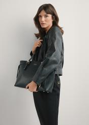 Czarna torebka shopper TOREC-1029-99(W26), widok produktu w rękach modelki. Widoczna połowa sylwetki.
