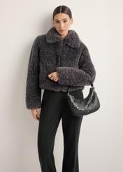 Czarna torebka damska hobo z biżuteryjnym akcentem TOREC-1326-99(Z26), widok skosu produktu na modelce. Widoczna połowa  sylwetki.