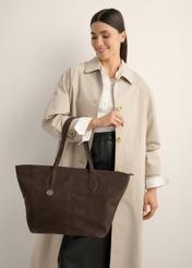 Brązowa torebka damska typu shopper TORES-1407-1I(Z26) - widok produktu z przodu, trzymanego przez modelkę w ręku, na jasnym tle. Widoczna sylwetka do połowy.