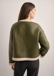 Krótki kożuch damski w kolorze khaki KOZDP-0015-8D(Z26), widok produktu od tyłu na modelce. Widoczna połowa sylwetki.