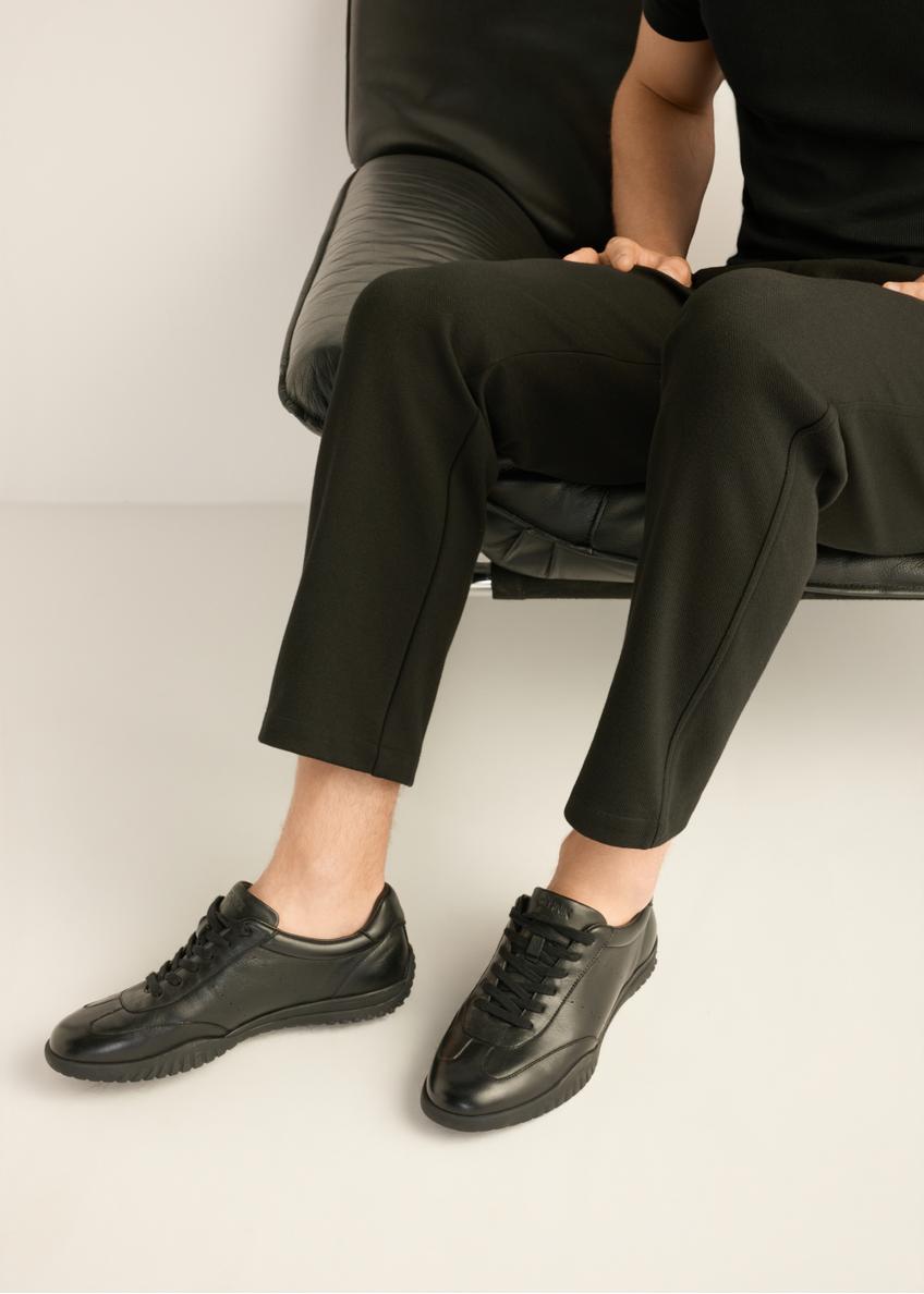 Czarne skórzane buty sportowe męskie BUTYM-0560-99(Z26) - widok produktu z z boku, na stopach modela, na jasnym tle. 